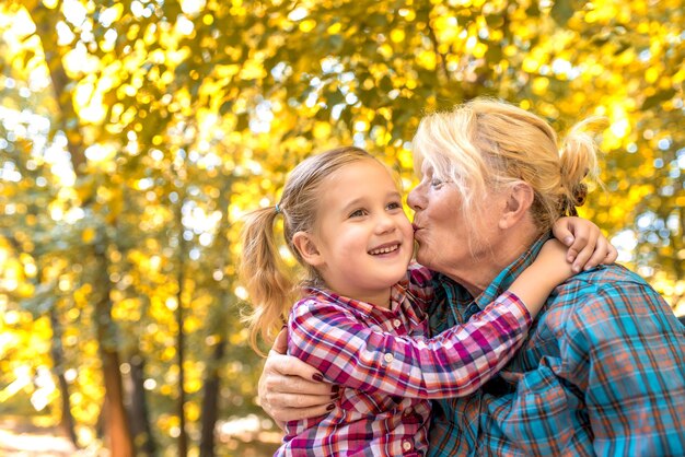 Abuela besando a su nieto femenino sonriente en el parque