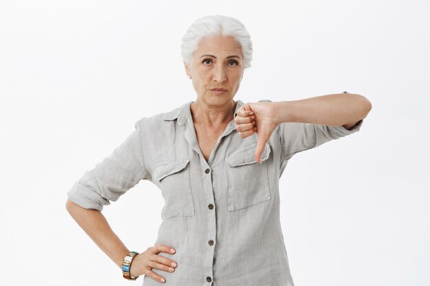 Abuela decepcionada mostrando los pulgares hacia abajo y haciendo muecas disgustada