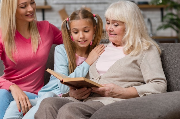 Abuela y familia sentados en un sofá y leyendo un libro