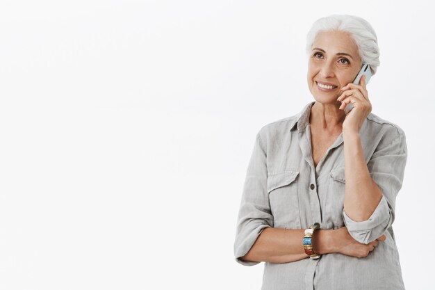 Abuela feliz alegre hablando por teléfono móvil y sonriendo