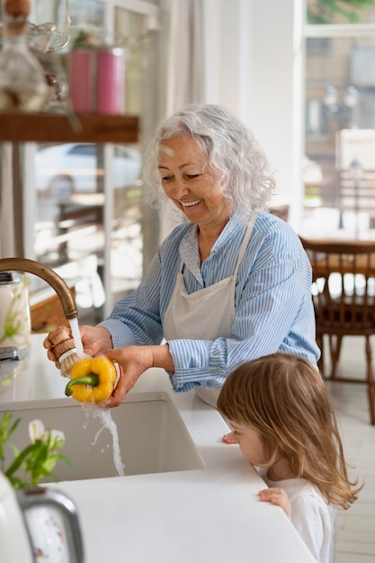 Foto gratuita abuela lavando verduras en la cocina