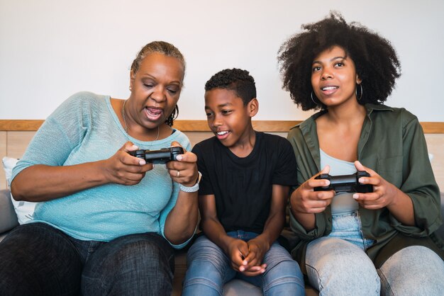 Abuela, madre e hijo jugando videojuegos en casa.