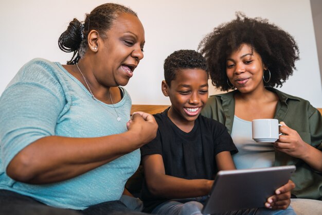 Abuela, madre e hijo tomando una selfie con tableta digital.