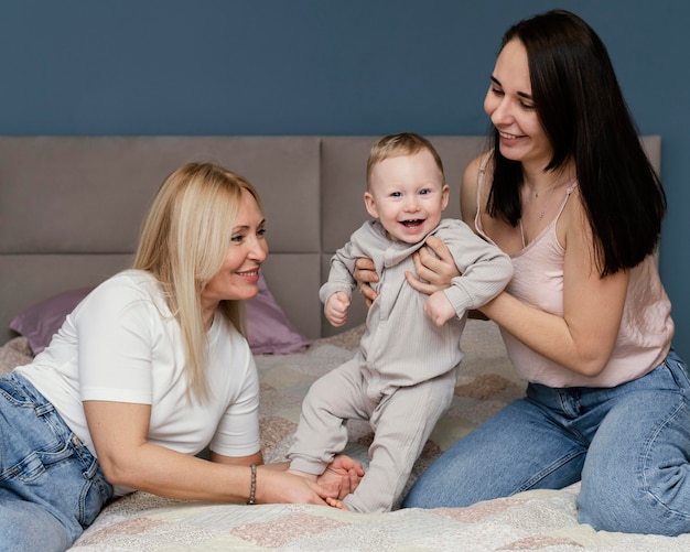 Abuela y madre jugando en la cama con nieto