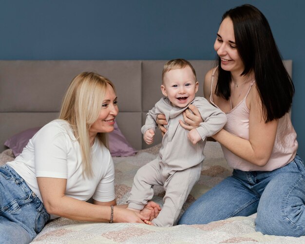 Abuela y madre jugando en la cama con nieto