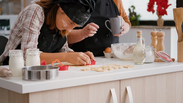 Abuela mostrando cómo usar la forma de las cookies a su nieto