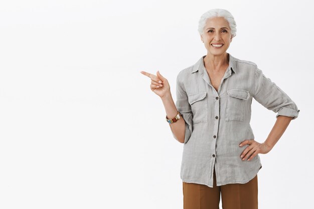 Abuela muy sonriente señalando con el dedo a la izquierda y mostrando publicidad