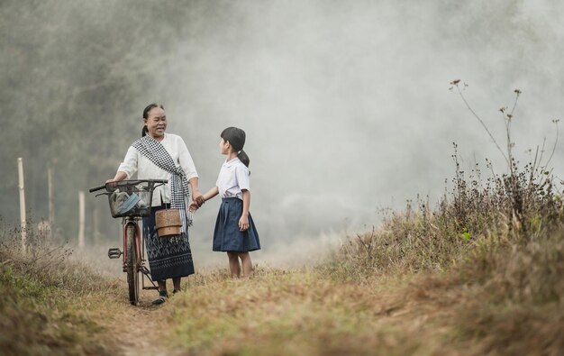 Abuela y nieta caminan por los campos con bicicletas.
