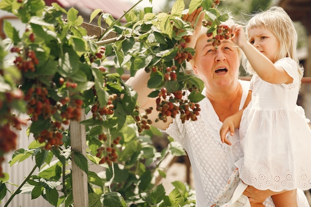 Abuela y nieta juntas, abrazándose y riendo alegremente en un jardín floreciente en verano. Estilo de vida familiar al aire libre.