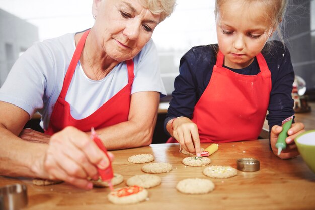 Abuela con niña decorando galletas navideñas