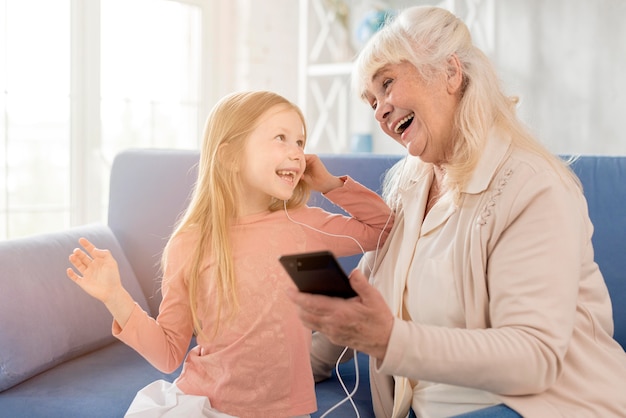 Foto gratuita abuela y niña escuchando música en el móvil