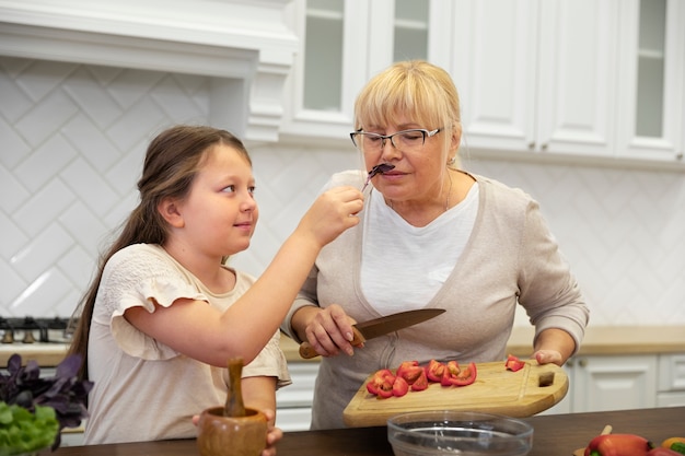 Abuela y niña de tiro medio cocinando