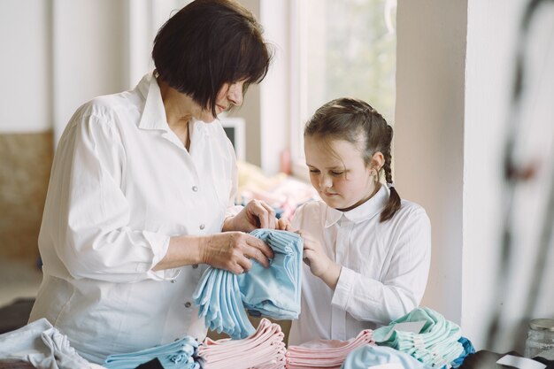 Abuela con pequeña nieta mide la tela para coser