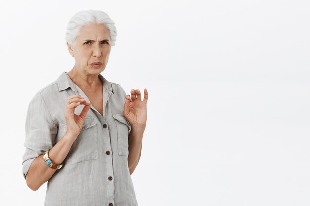 Abuela quisquillosa disgustada haciendo muecas y mirando con aversión