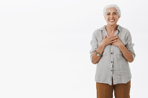 Foto gratuita abuela sonriente mirando agradecida, tocando el pecho complacido