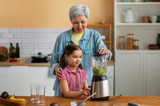 Abuela de tiro medio y niña cocinando juntas