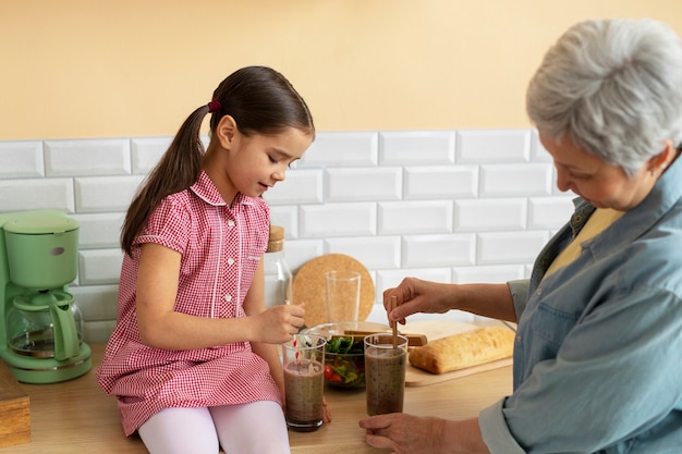 Abuela de tiro medio y niña cocinando juntas