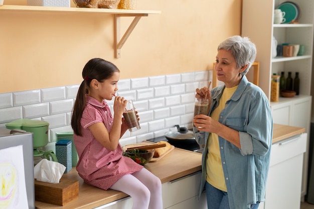 Abuela de tiro medio y niña cocinando juntas