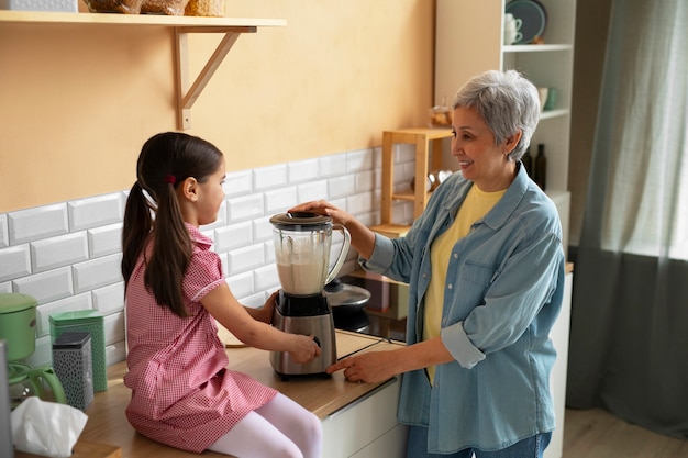 Abuela de tiro medio y niña cocinando juntas