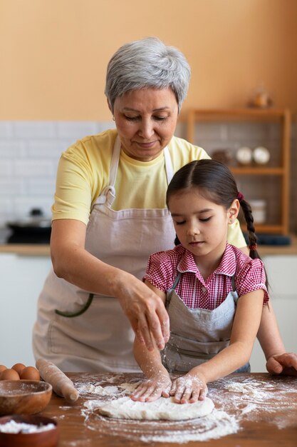 Abuela de tiro medio y niña cocinando juntas