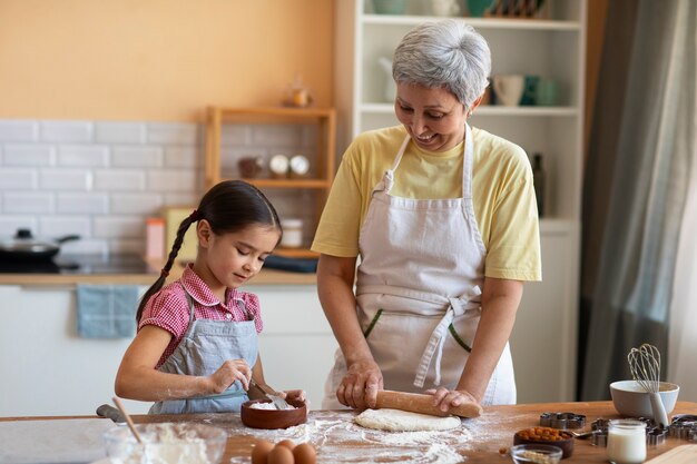 Abuela de tiro medio y niña cocinando juntas