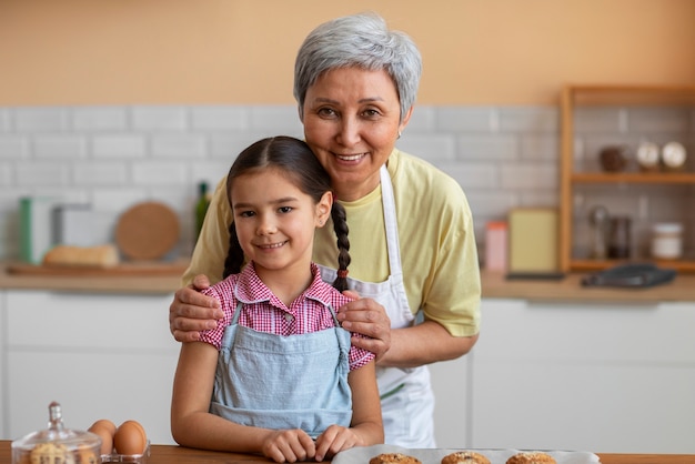 Abuela de tiro medio y niña cocinando juntas