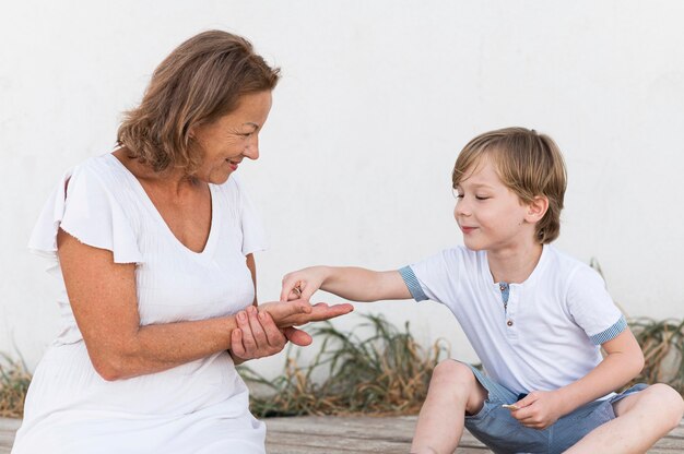 Abuela de tiro medio y niño con conchas