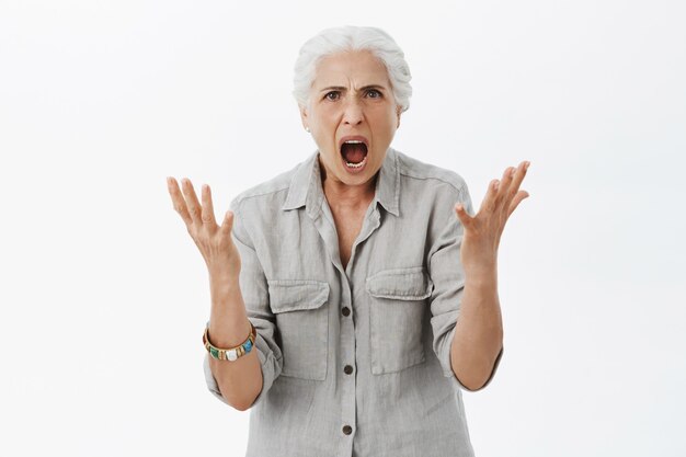 Abuelita enojada cabreada dándose la mano y gritando, enojada con la persona