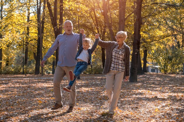 Abuelo y abuela jugando con su nieto en un parque