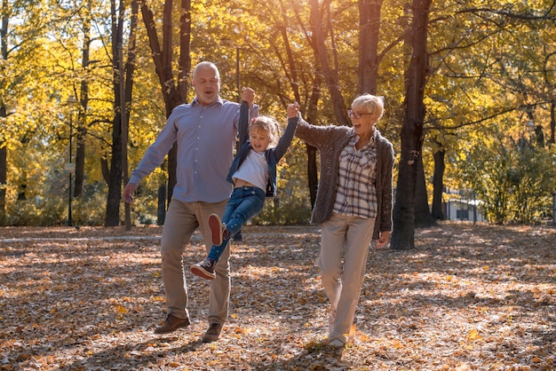 Abuelo y abuela jugando con su nieto en un parque