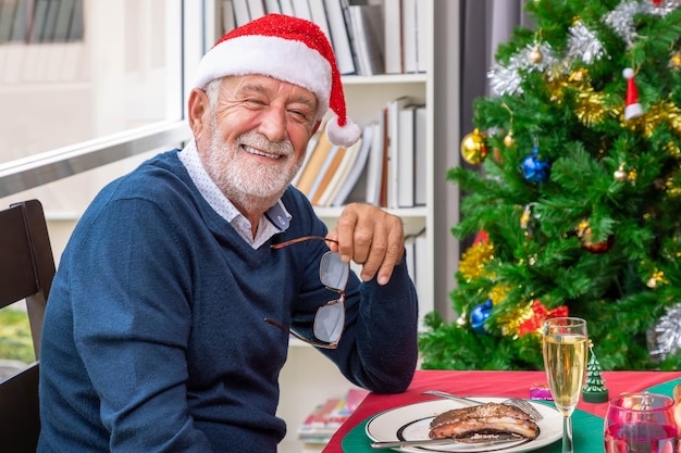 El abuelo anciano y la feliz familia extendida de varias generaciones cenando juntos para celebrar juntos las vacaciones de Navidad