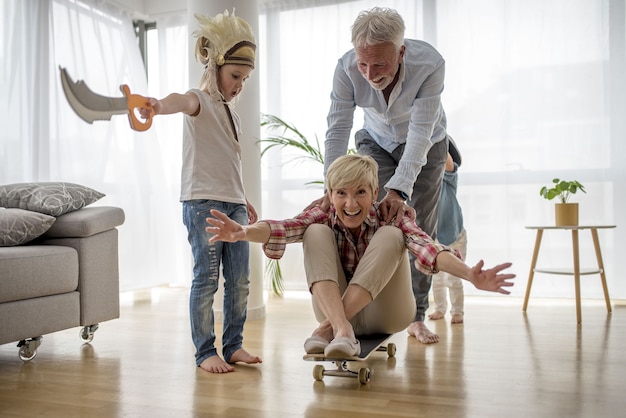 Abuelo caucásico empujando a la abuela en patineta dentro con su nieto vistiendo traje de pirata