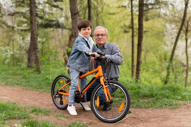 Foto gratuita abuelo enseñando a su nieto a andar en bicicleta