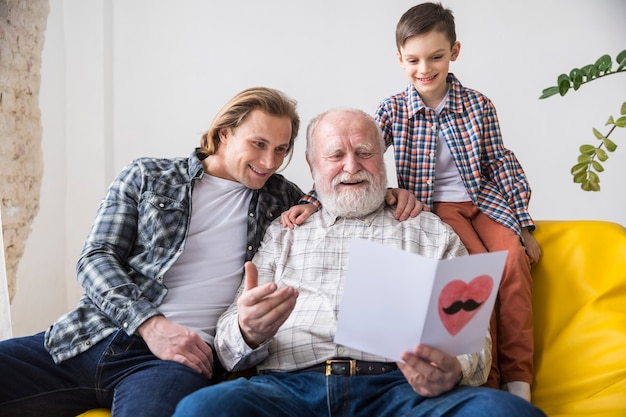 Abuelo feliz mirando a través de tarjetas de felicitación hechas a mano