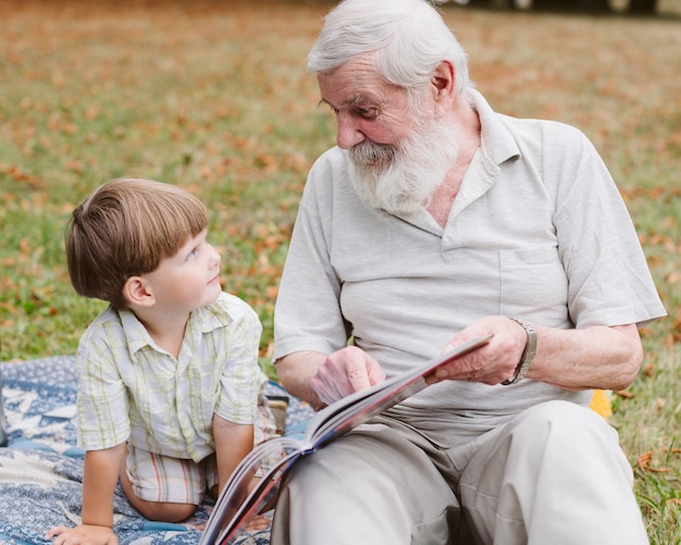 Abuelo leyendo para nieto en el parque
