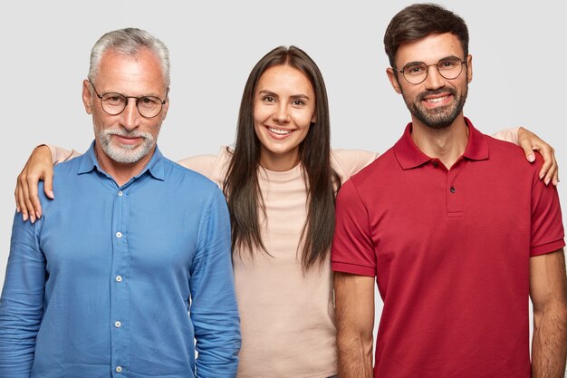 Abuelo, nieta y nieto amistosos se paran cerca y se abrazan