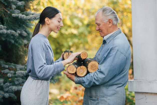 Abuelo con nieta en un patio con leña en manos