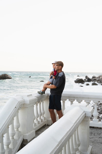 Foto gratuita abuelo con nieto y mirando al mar