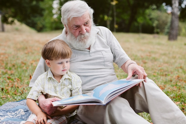 Abuelo y nieto en parque leyendo