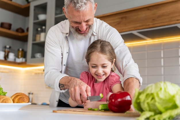 Abuelo y niña de tiro medio en la cocina