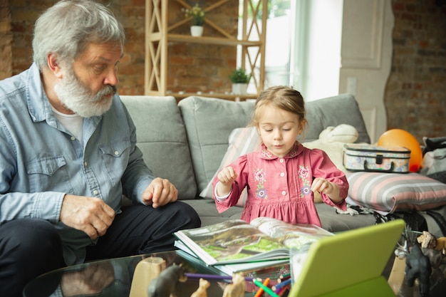 Abuelo y niño jugando juntos en casa. La felicidad, la familia, la relación, el concepto de educación.