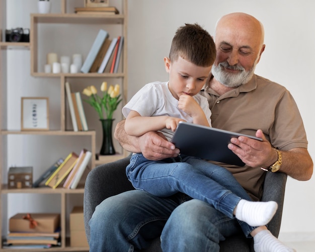 Abuelo de tiro medio con niño y tableta