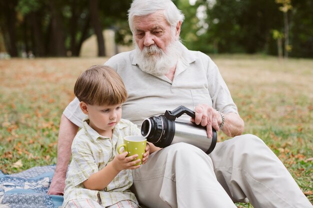 Foto gratuita abuelo vertiendo té para nieto