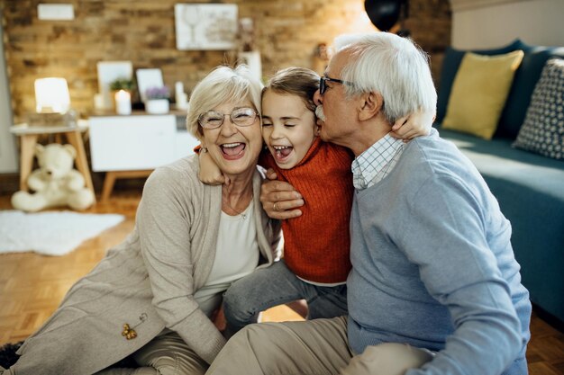 Abuelos alegres y nieta divirtiéndose juntos en casa