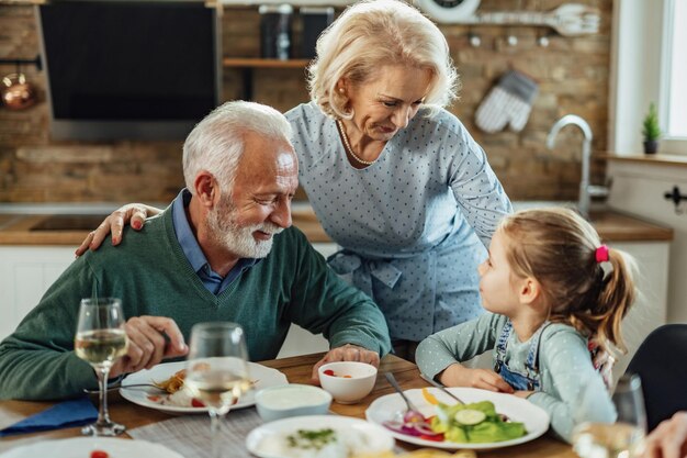 Los abuelos felices y su nieta se comunican mientras almuerzan en el comedor.