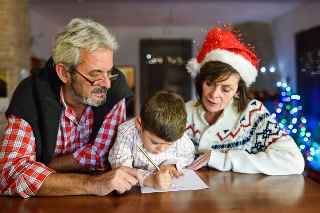 Abuelos y nieto escribiendo la carta a papa noel