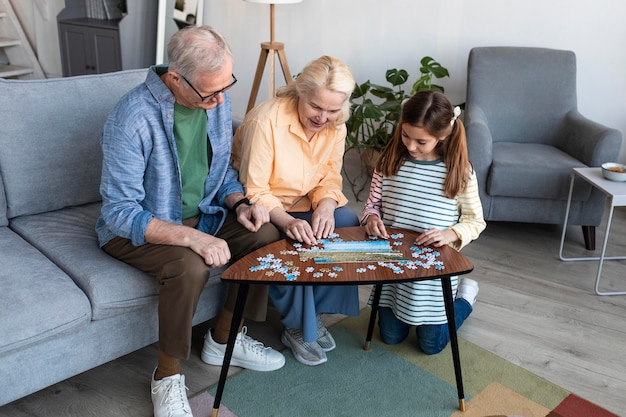 Abuelos y niña haciendo puzzle full shot