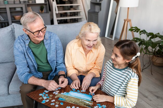 Abuelos y niña haciendo rompecabezas tiro medio