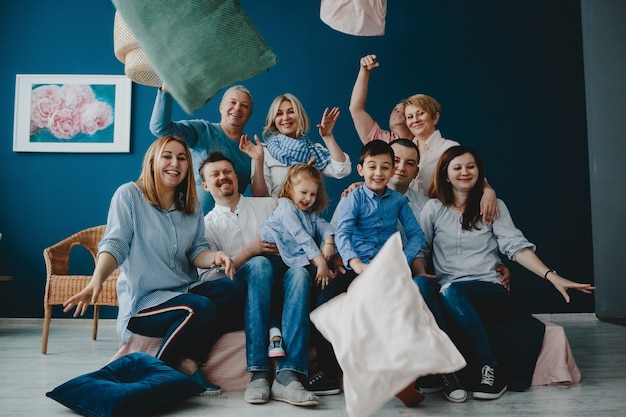 Abuelos, padres y sus pequeños hijos se sientan juntos en la cama en una habitación azul