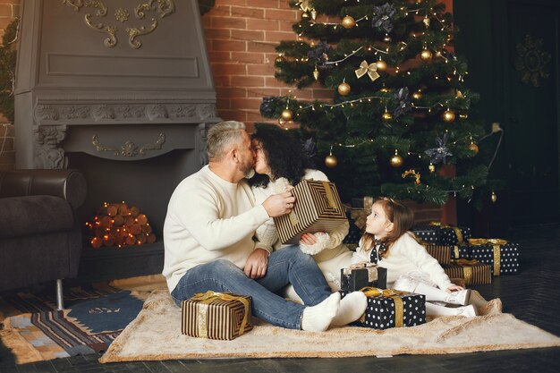 Abuelos sentados con su nieta. Celebrando la Navidad en una casa acogedora.